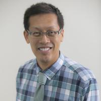 Headshot of man in collard shirt wearing glasses